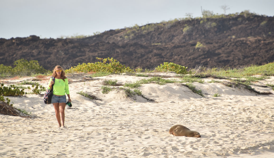 Cerro Brujo - San Cristobal in Galapagos Islands, tourist walking in the beach and watching the sea