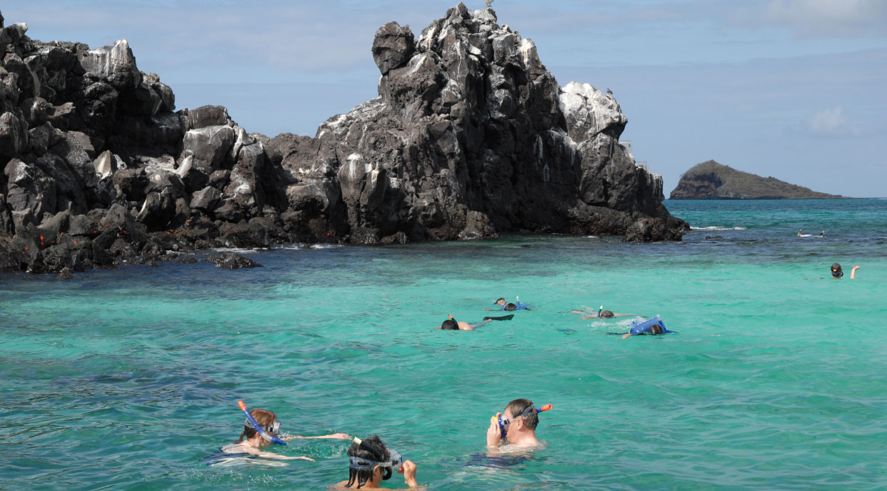 Devil's Crown - Floreana in the Galapagos Islands with tourist doing snorkeling and the crown in the background