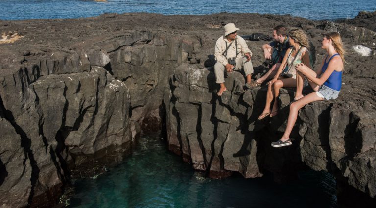 Egas port rocky terrain and sea, conversation betwen guide and tourist